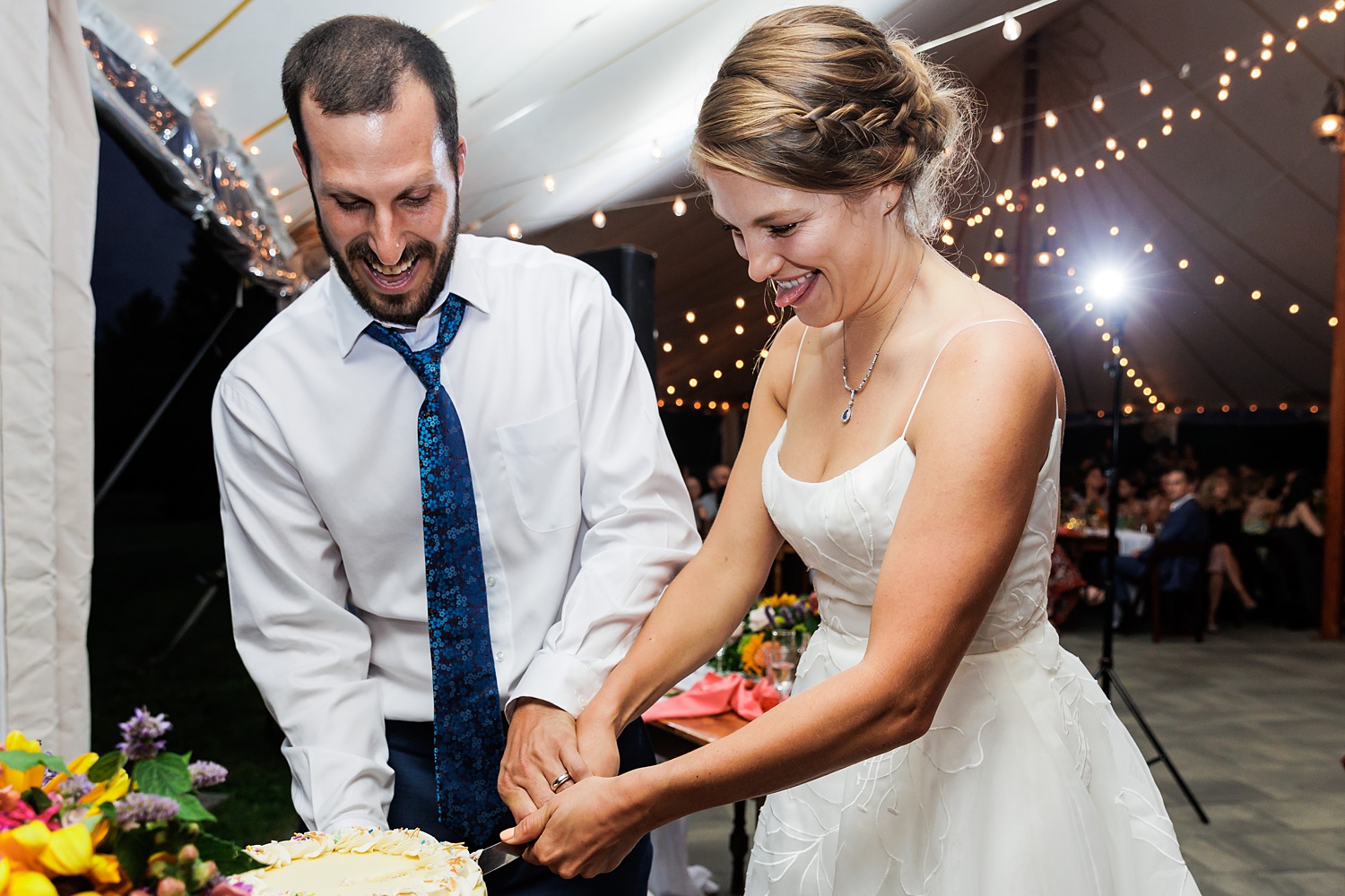 Cutting the wedding day cake under the tent