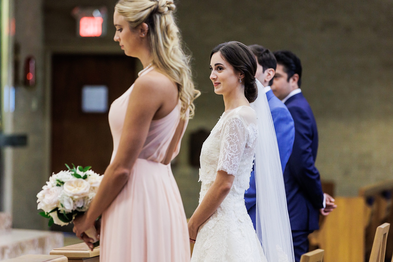The bride smiles at her sister while at the altar