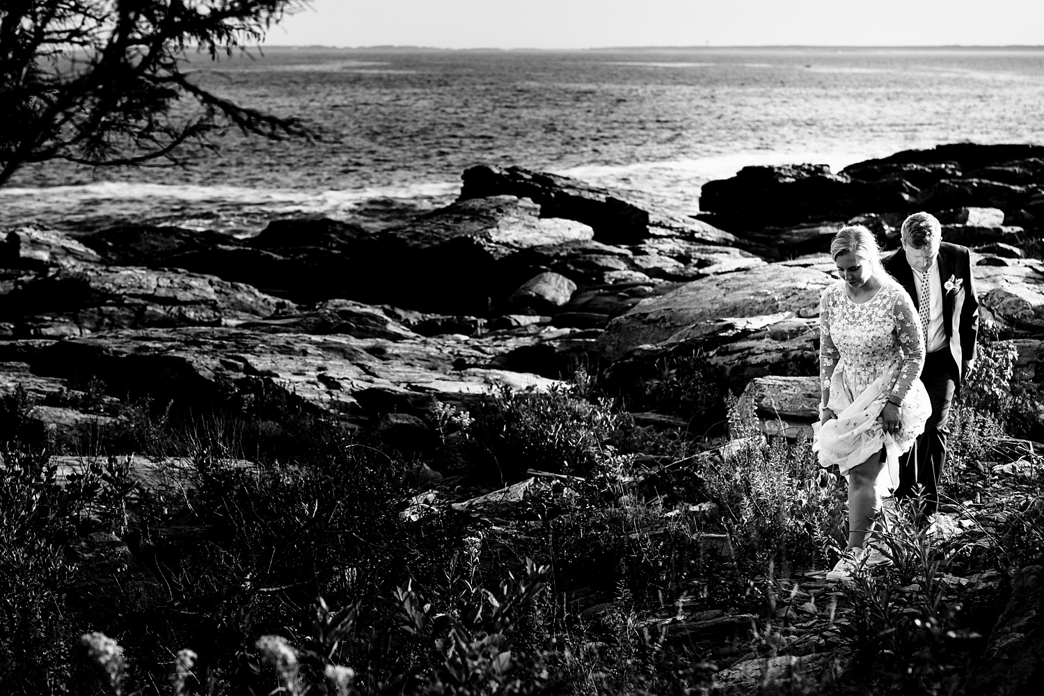 Bride and groom walk among the rocks in Maine