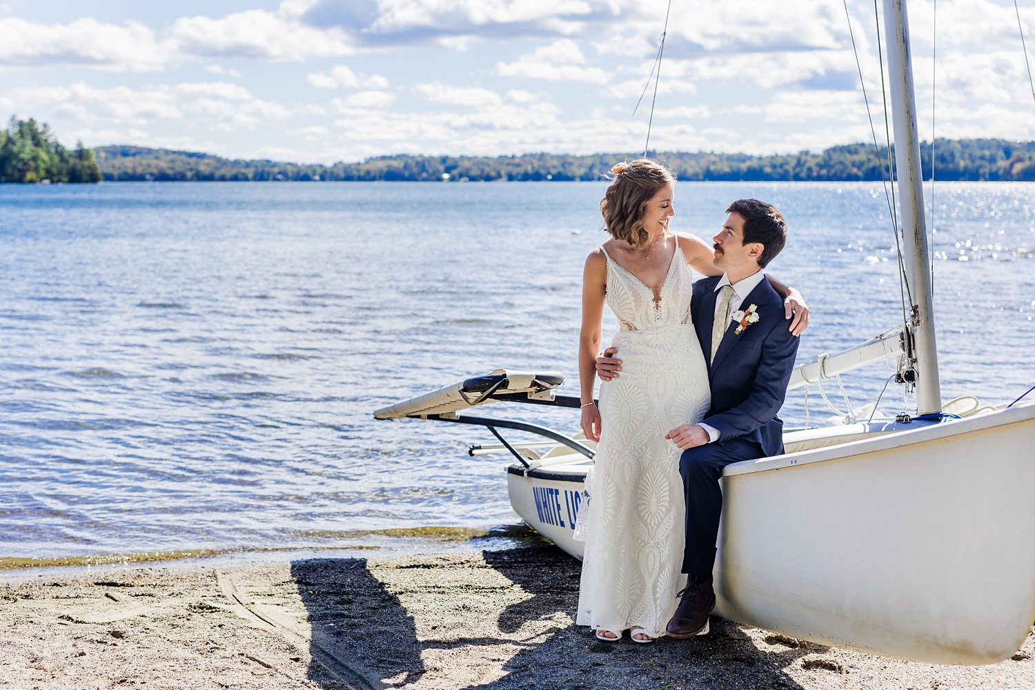 Bride and groom settle on a boat sitting shoreside on the lake