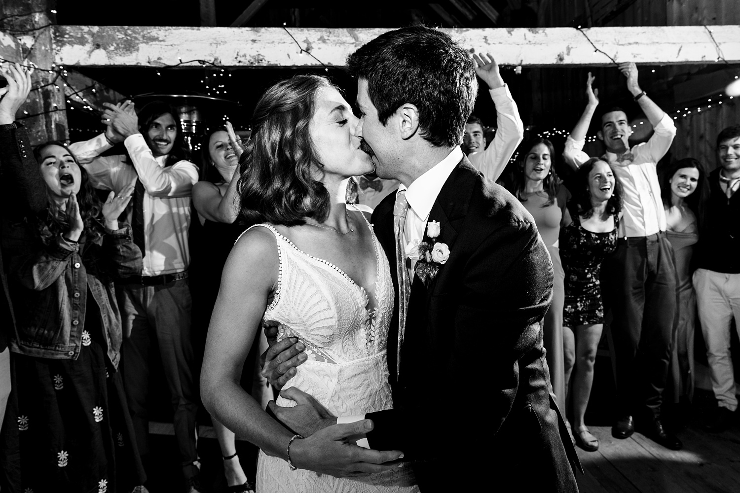 Bride and groom kiss in front of the celebrating guests on their wedding day