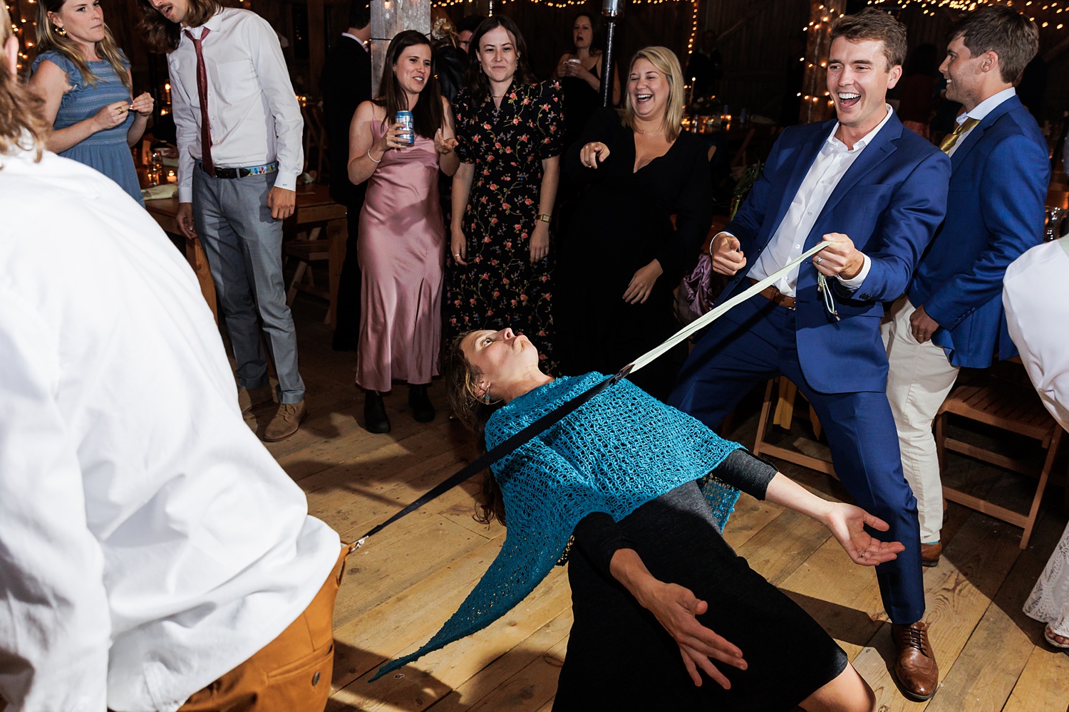 Limbo games using a groomsman's suspenders at the fall wedding reception