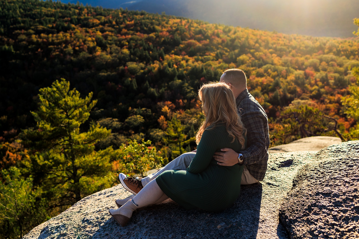 Taking a seat on a cliff that overlooks the colorful fall views at Cathedral Ledge NH