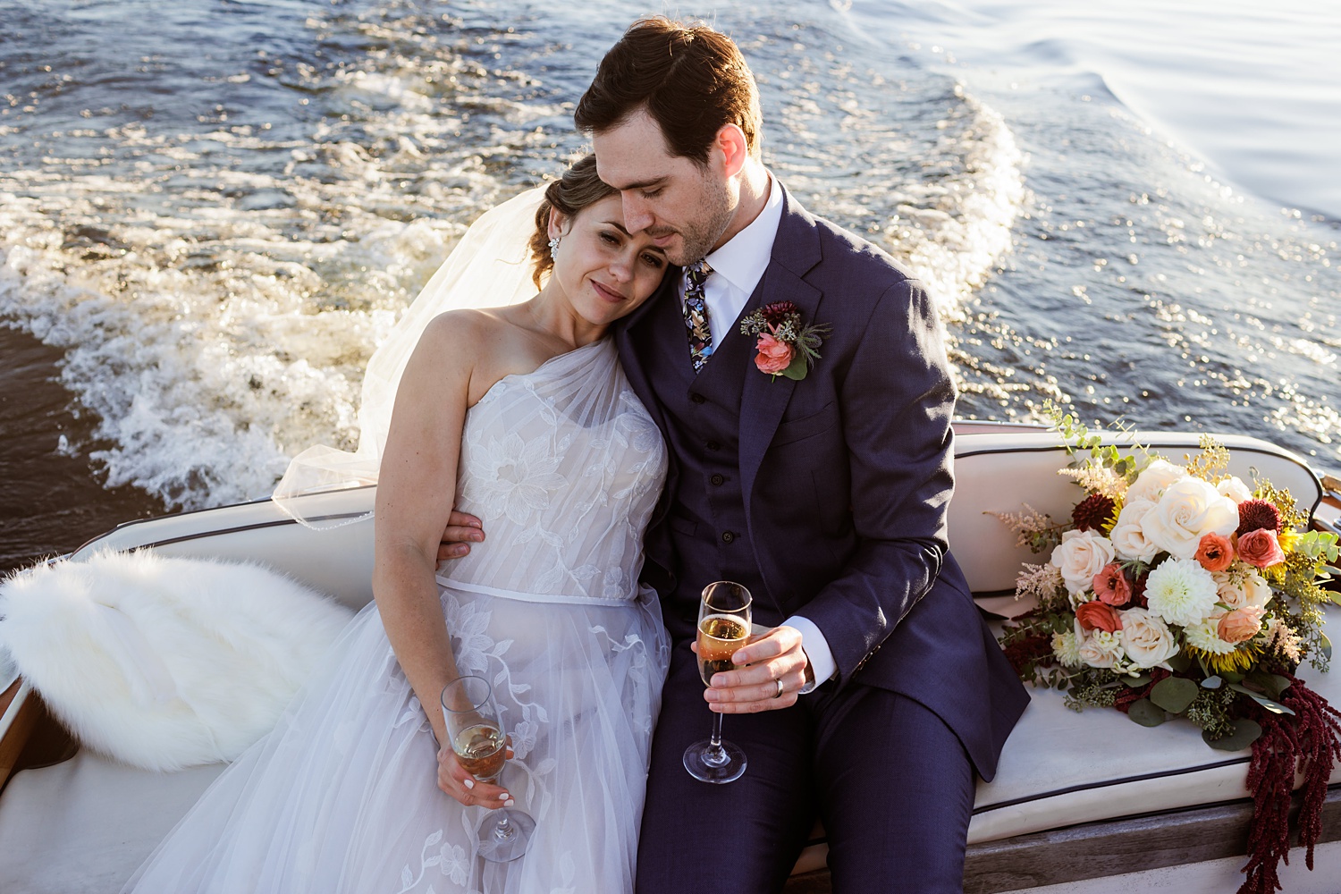 The newlyweds snuggle one another on the boat after the ceremony at Migis Lodge Resort Maine