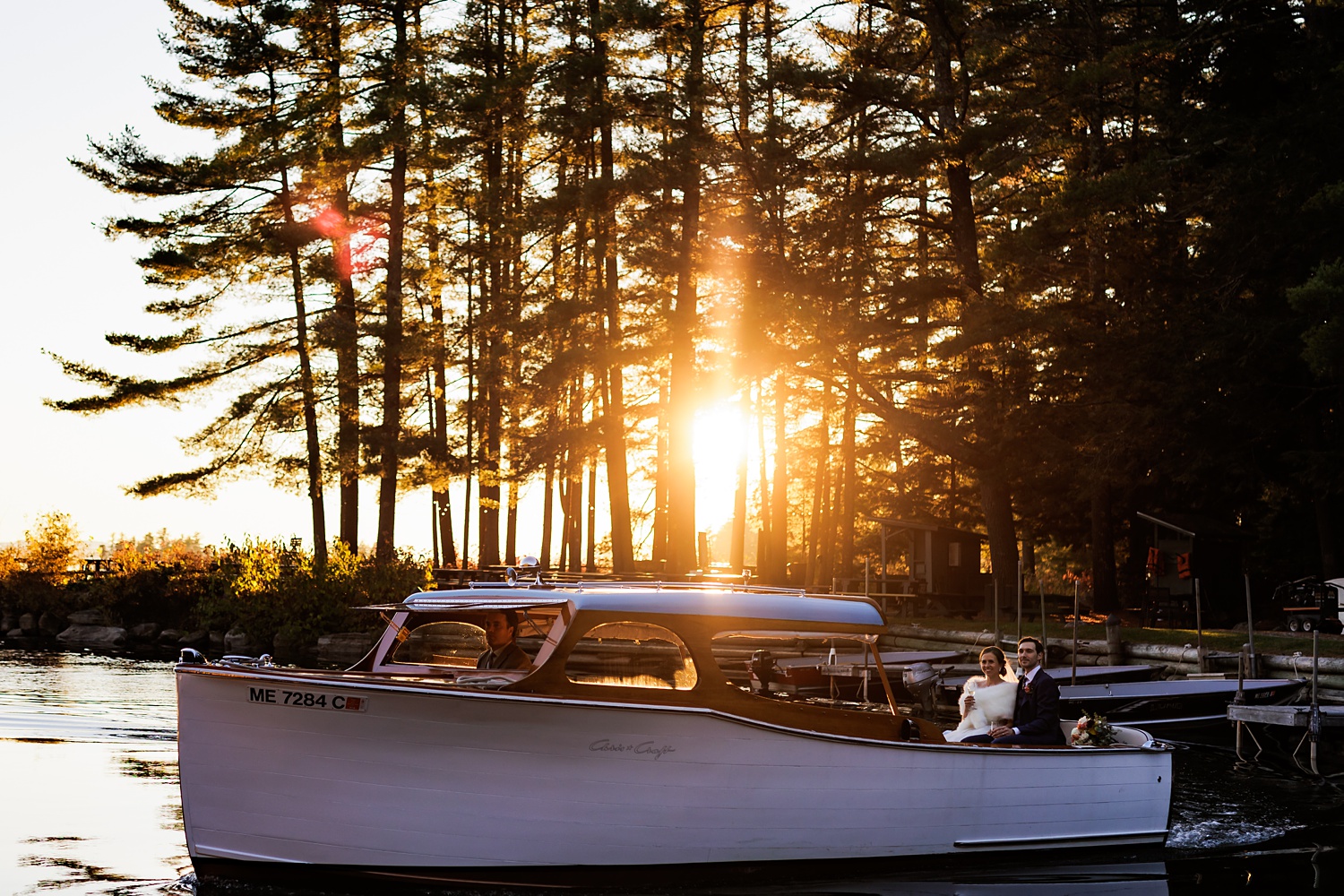 The bright orange sun on the wedding day of the couple out on the waters of Sebago Lake Maine