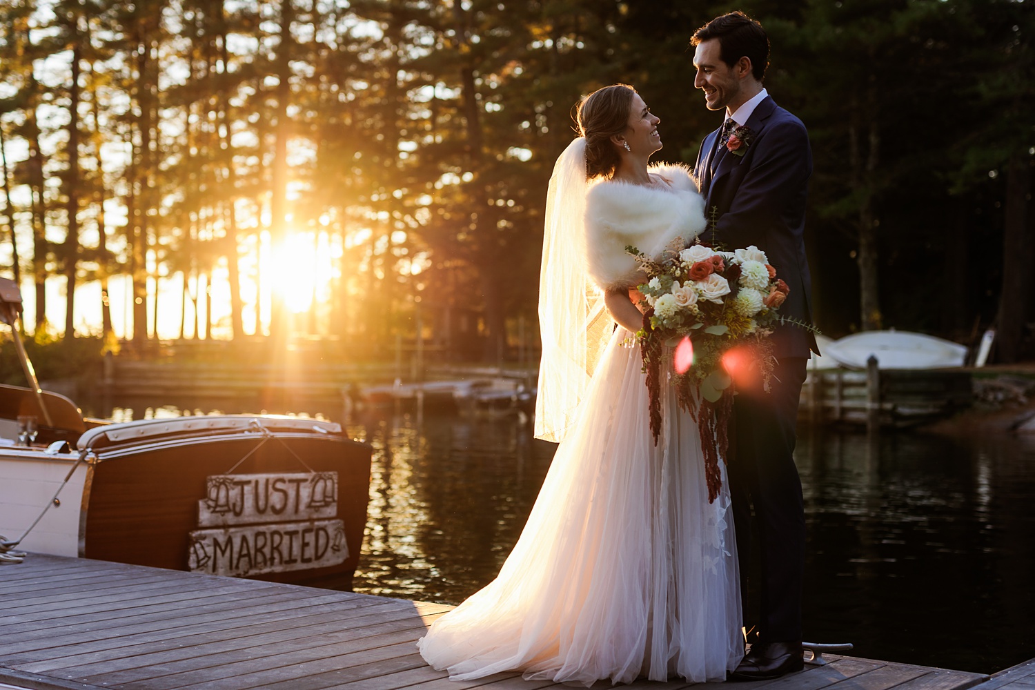 The couple share a moment in front of the setting sun and Migis Lodge's boat on their wedding day