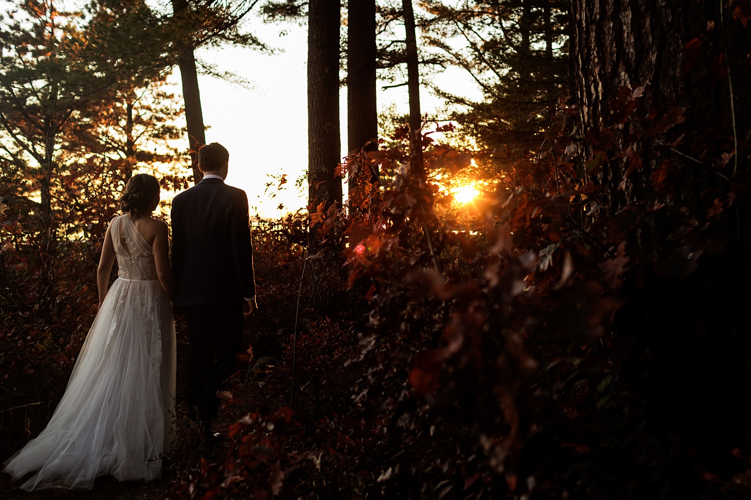 The sun sets as the couple walks through the woods at Maine's Migis Lodge Resort