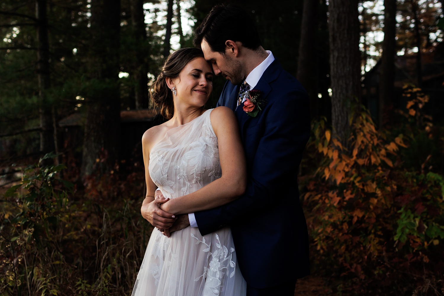 The bride and groom get in close while in the woods of Migis in Maine with a beautiful sunset