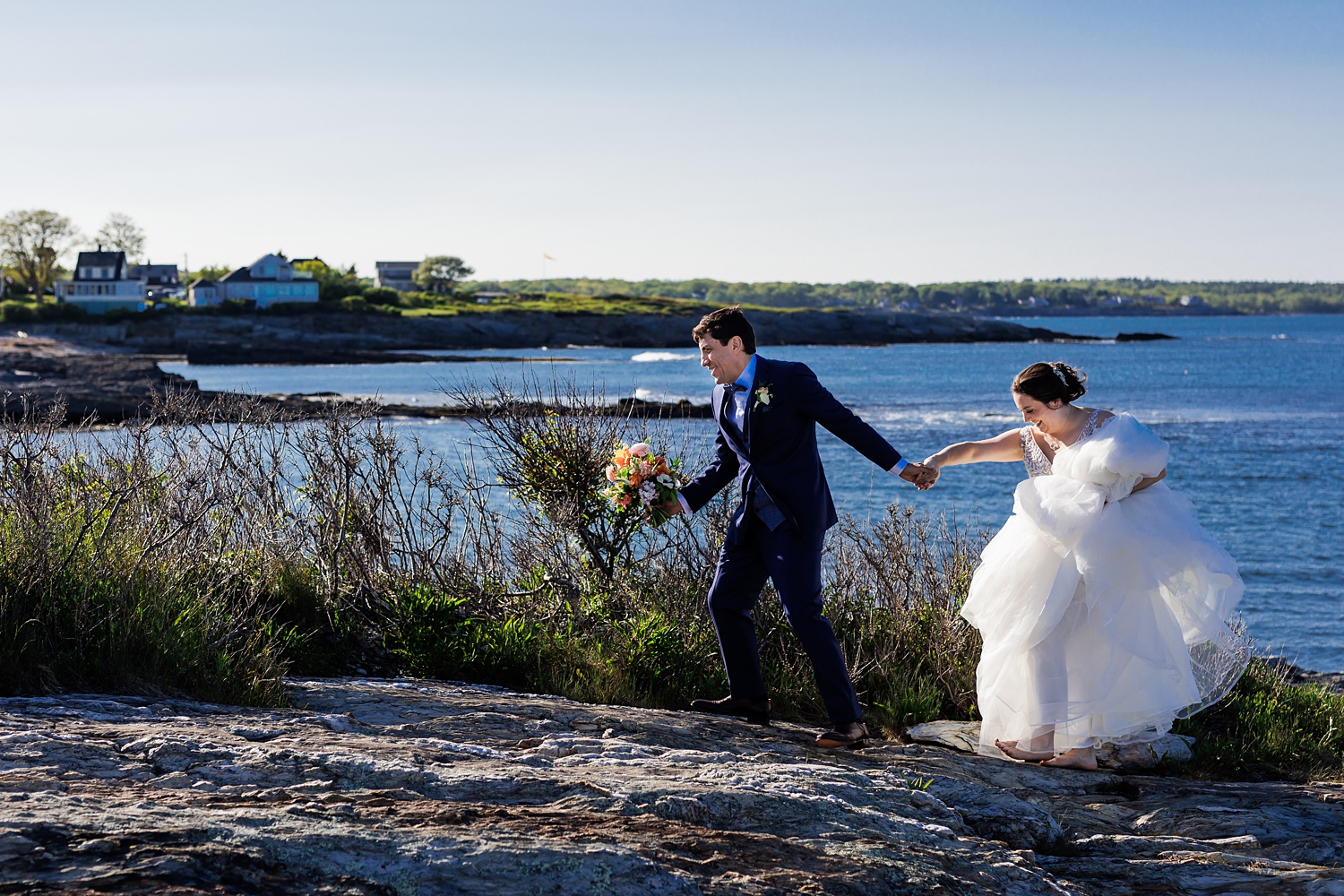 Newlyweds climb around on the rocks in Cape Elizabeth