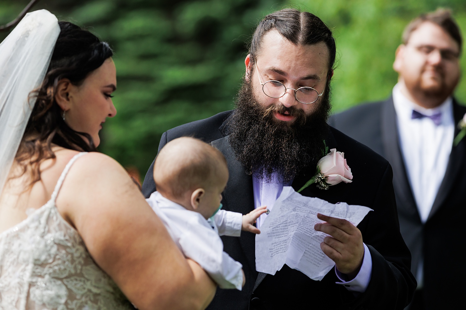 The groom reads his vows while his son reaches for the paper