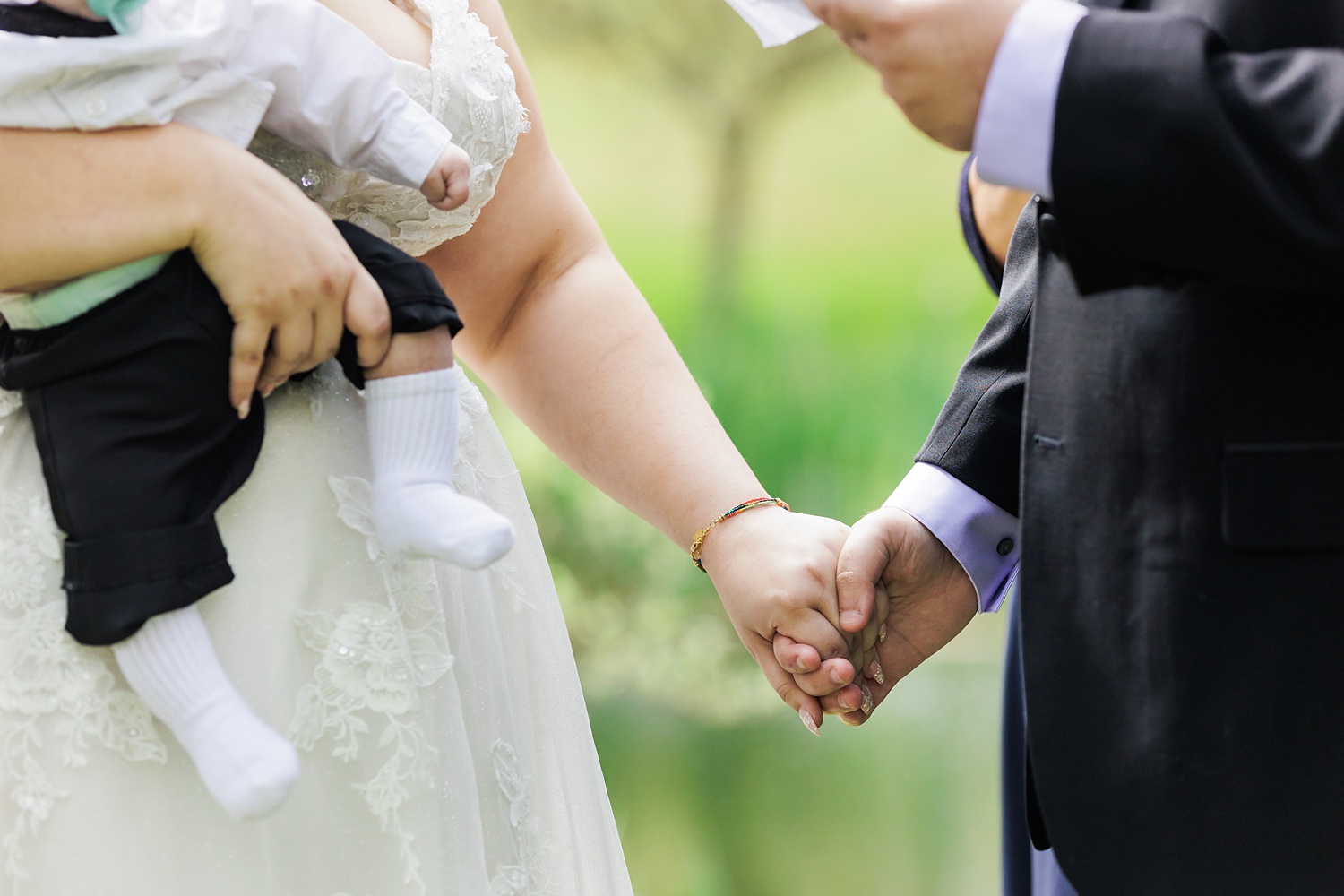 The couple hold hands and their son during the wedding ceremony
