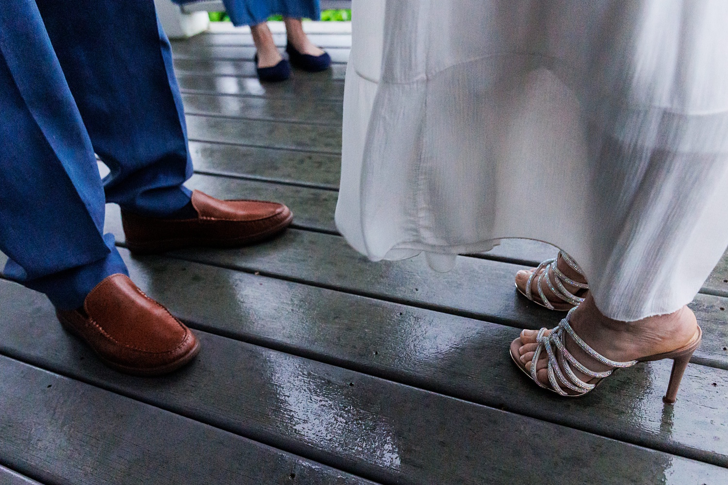 The wedding couple stand on a patio for their sunrise elopement as it rains