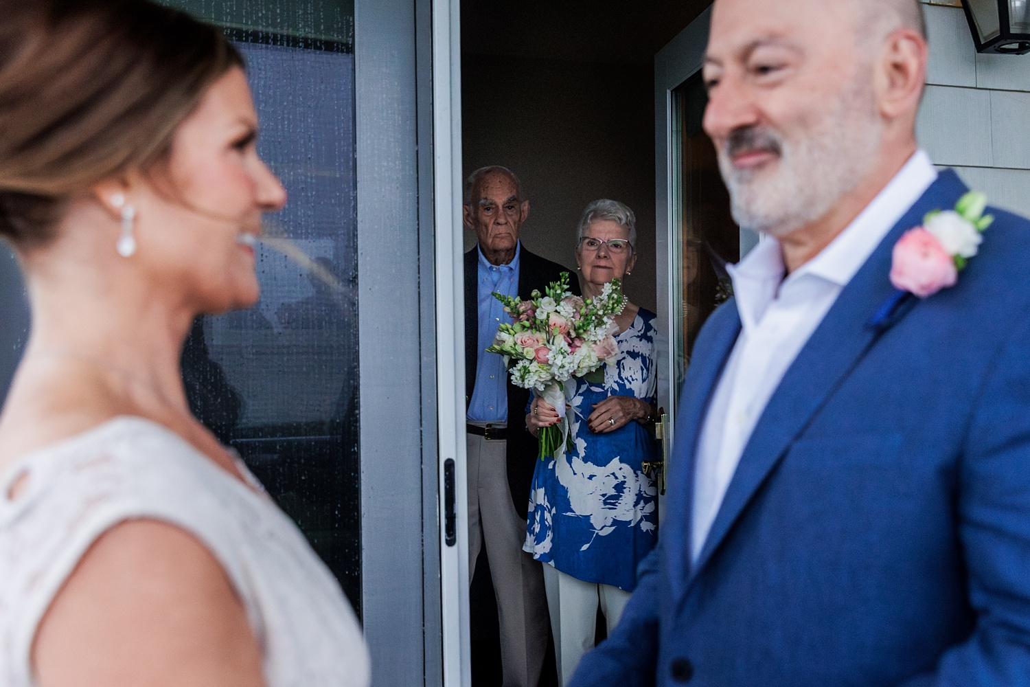 The parents of the bride watch the couple read their vows on the patio of the Beachmere Inn hotel room they used for their elopement in Maine