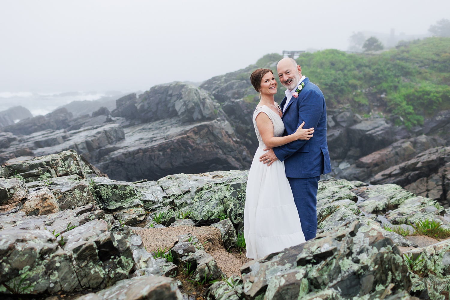 The couple smiles big on the rocks at Marginal Way Maine in Ogunquit after eloping