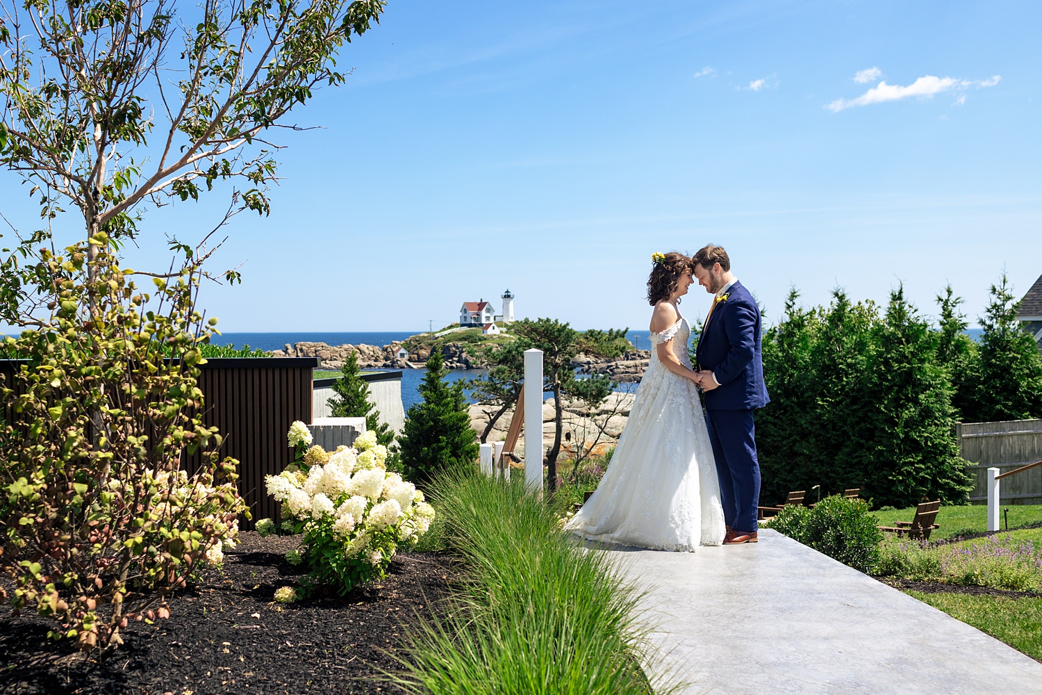 The newly married couple get close together at a view of the Nubble Lighthouse in York Maine