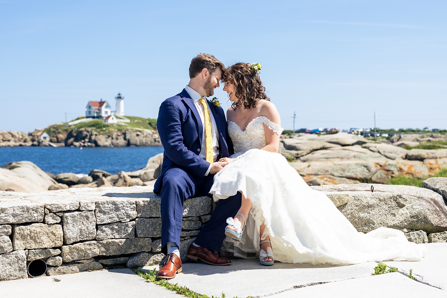 The bride and groom sit with a view of the Nubble Lighthouse in York Maine