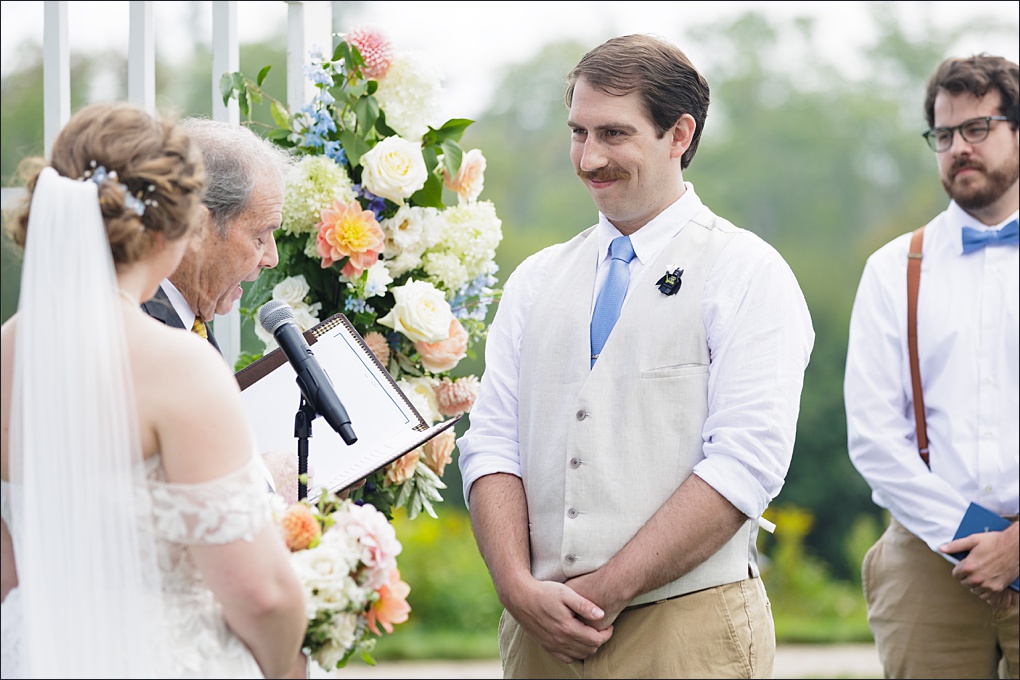 The groom smiles at the bride during their ceremony